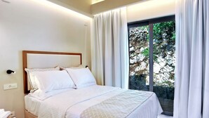 A neatly made bed with white linens in a hotel room with a large window and curtains. - Suite Demi - Demar Suites (Vlicho)