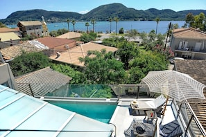 A rooftop pool with a glass barrier, a white umbrella, and a view of a lake with boats. - Suite Demi - Demar Suites (Vlicho)