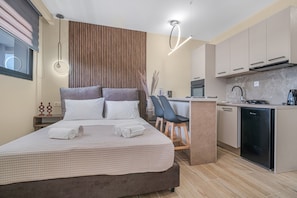 Une chambre d’hôtel moderne équipée d’un lit, d’une table de chevet et d’une kitchenette.