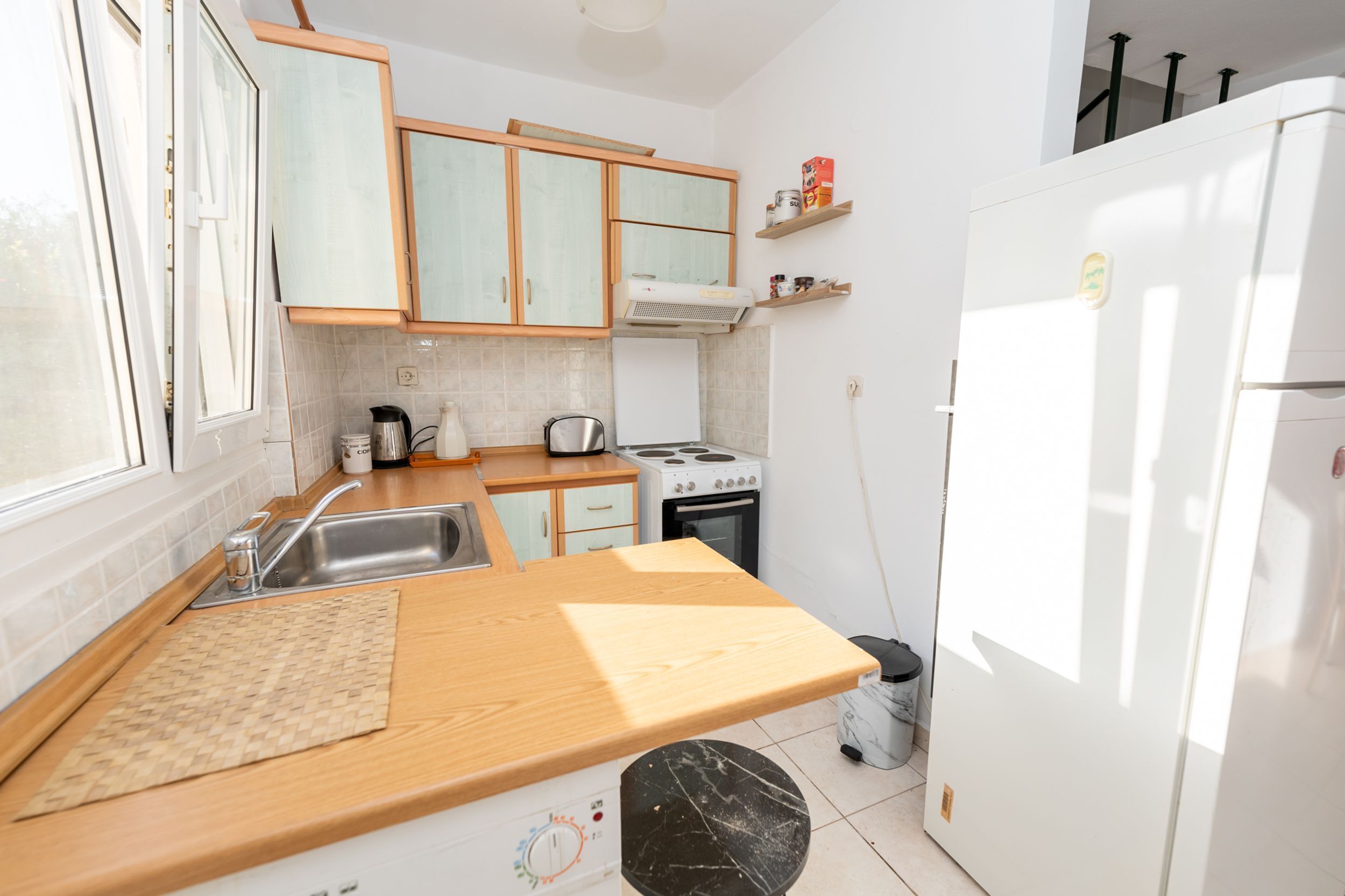 A compact kitchen with a sink, stove, and cabinets.