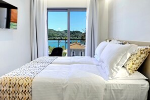 A hotel room with a bed, a TV, and a view of a mountainous landscape. - Suite Christina - Demar Suites (Vlicho)
