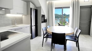 Une cuisine moderne avec des meubles blancs, un four encastré et une grande fenêtre donnant sur un paysage magnifique.