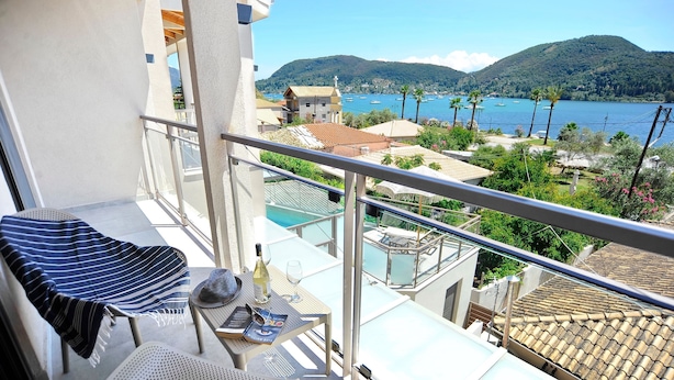 Un balcon donnant sur une ville côtière, une piscine et une montagne en arrière-plan.