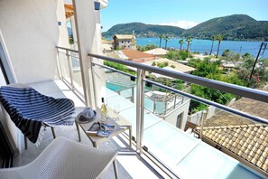 Ein Balkon mit Blick auf eine Küstenstadt, einem Pool und einem Berg im Hintergrund.