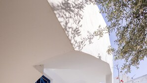Un edificio blanco con una escalera y barandilla azules, que conduce a una puerta con un persiano azul.