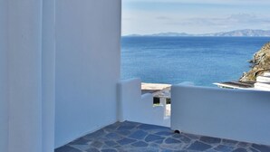 A balcony with stone flooring and a white wall, overlooking a clear blue sea and distant mountains. - Tinos Portraits Kato Meria (Exomvourgo)