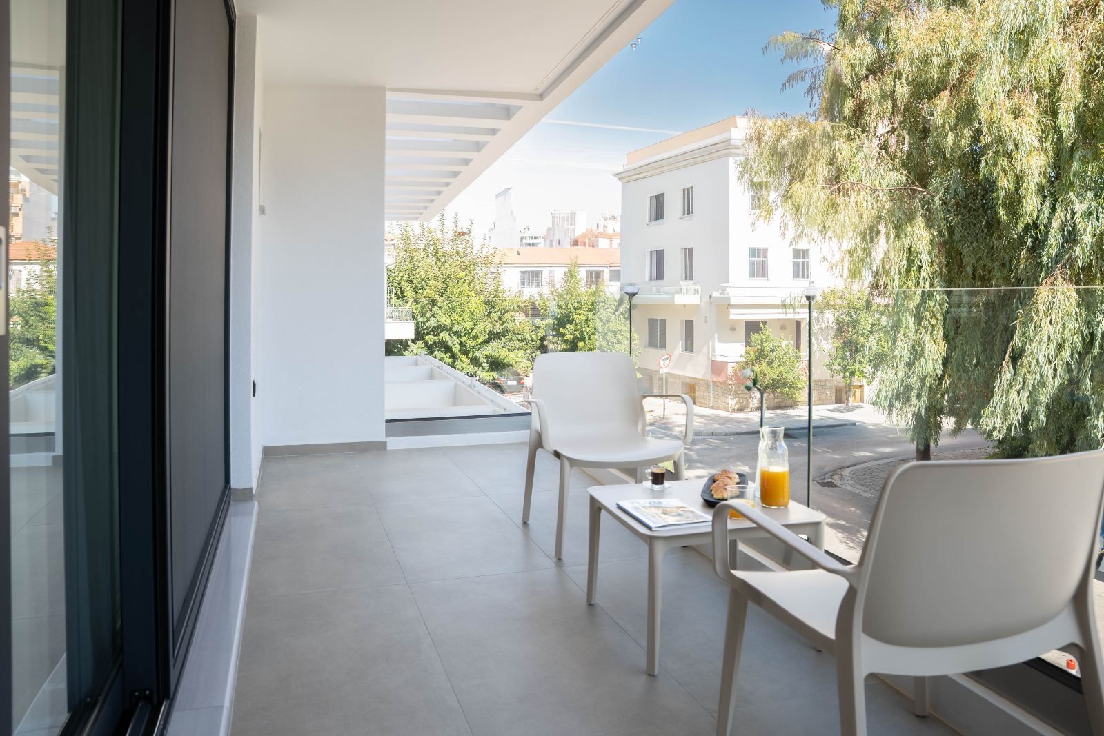 A balcony with two chairs, a table, and a glass of orange juice.
