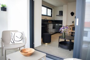 Una cocina moderna con electrodomésticos negros, un comedor con una mesa redonda y sillas, y un taburete pequeño.