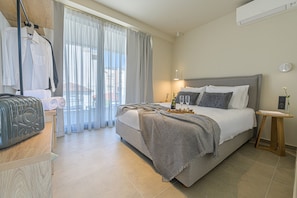Una habitación de hotel ordenada con cama, mesita de noche y ventana con cortinas.