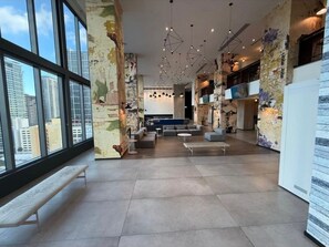 A spacious lobby with high ceilings, modern lighting fixtures, and a view of the city through large windows. - Miami-Brickell Luxury 2BR-2BATH with skyline VIEWS (Miami)