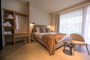 Una habitación de hotel moderna con cama, zona de estar, armario y ventana con cortinas.