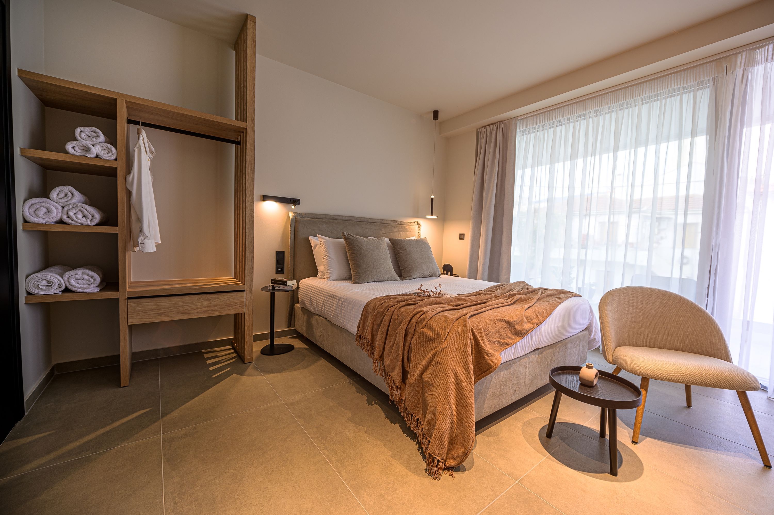 Une chambre d’hôtel comprenant un lit, un coin salon, une armoire avec des serviettes et une fenêtre avec des rideaux.
