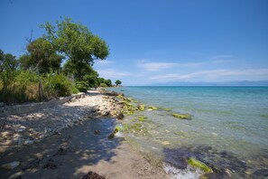 A beach with clear water, rocky shore, and trees. - Jokos House in Roda with 2 bedrooms and 2 bathrooms (Roda)