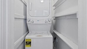 Una lavatrice e asciugatrice a carica frontale, di colore bianco e dalle dimensioni compatte, con manopole di controllo e un'etichetta visibile sull'efficienza energetica.