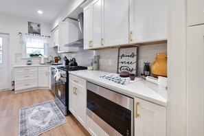 A modern kitchen with white cabinetry, stainless steel appliances, and a decorative sign on the countertop.