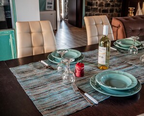 Taula de menjador coberta amb plats verds blavosos, glops de vi i una ampolla de vi blanc.