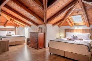 Camera da letto con due letti, travi in legno, un lucernario e un comò.