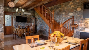 Ein Essbereich mit einer Holztreppe, Steinwänden und einem für eine Mahlzeit gedecktem Tisch.