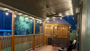 Eine Holzterrasse mit einem Pavillon, Sitzmöbeln und Blick auf ein Gewässer.