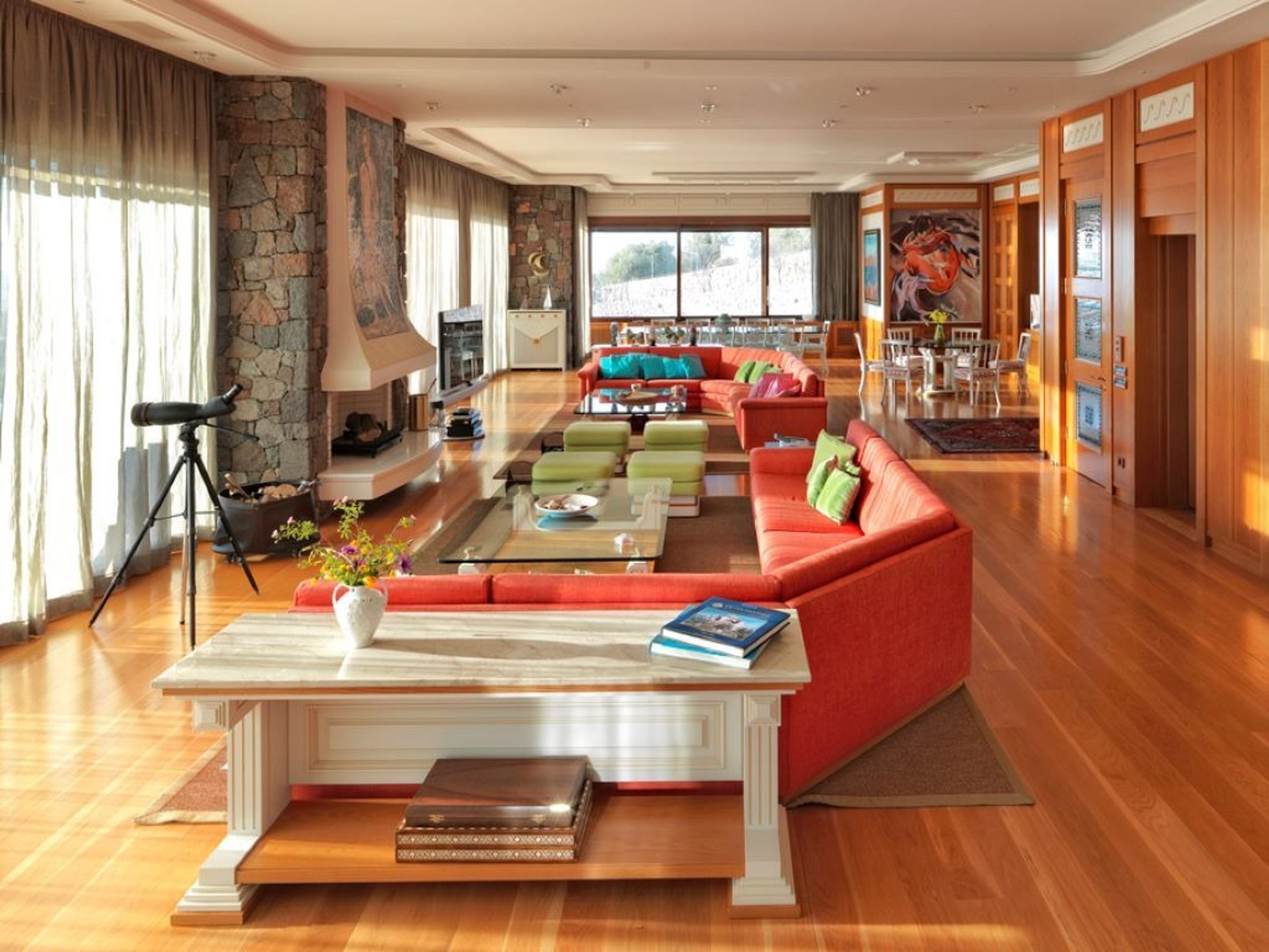 A spacious living room with a red sofa, a coffee table, and a stone fireplace.