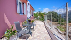 Un patio con una mesa y sillas, un edificio rosa y vistas al campo.