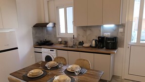 Uma cozinha moderna com área de refeições. Inclui máquina de lavar, cafeteira e fogão.