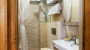 Een badkamer met een douche, toilet en wastafel.