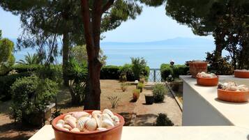 Eine Terrasse mit Terrakotta-Töpfen mit Muscheln, mit Blick auf einen Garten mit verschiedenen Pflanzen und Meerblick.