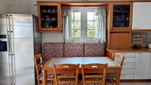Una cocina compacta con una mesa de comedor, sillas, un banco empotrado y un refrigerador.