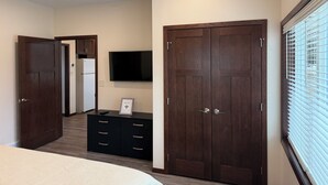 A bedroom with a bed, a dresser, a TV, and a wardrobe.