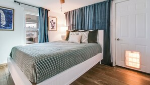Un dormitorio con cama, ventilador de techo, una puerta y una ventana.