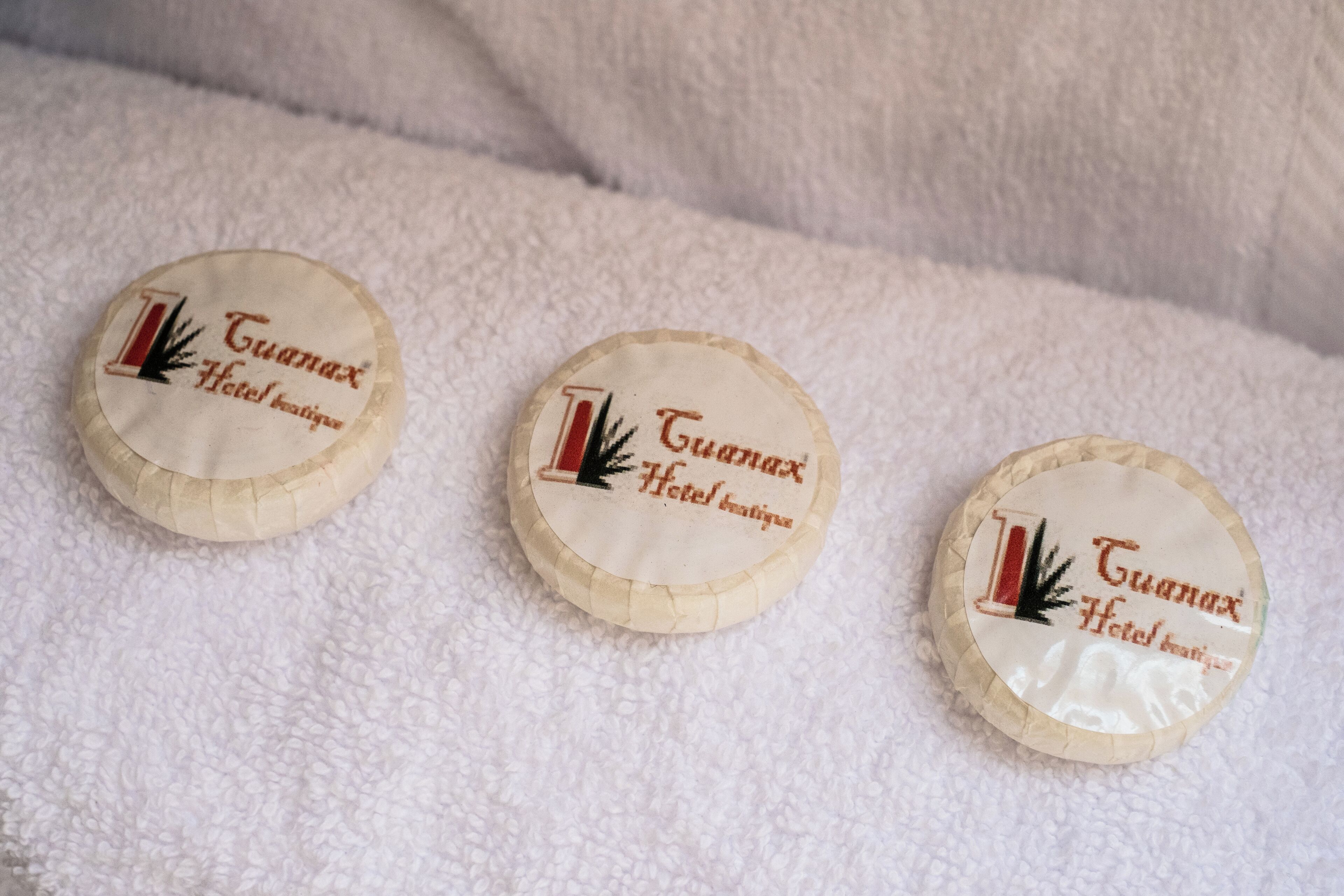 Tres objetos circulares con el texto 'Guamax Hotel Boutique' y un logotipo de árbol.