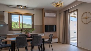 Una cuina moderna amb zona de menjador, un televisor penjat a la paret i una finestra gran.