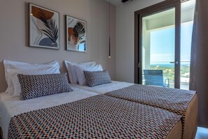 A double bed with patterned bedding, two framed artworks on the wall, and a balcony with a view. - Athel Panoramic view Villas Athina (Agia Paraskevi)