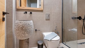 Une salle de bain moderne avec un lavabo en pierre, des toilettes et une douche à parois de verre.