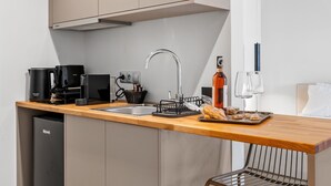 Une cuisine de taille réduite, dotée d’un plan de travail en bois, d’un évier encastré et d’un réfrigérateur compact.