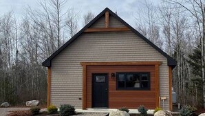 A small, single-story building with a gabled roof, a front door, and a large window. - Acadia Timber Cottages #55 - Minutes to Acadia National Park! (Trenton)