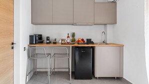 A compact kitchen with a wooden countertop, two metal chairs, a black refrigerator, and a built-in oven. - garden & pool view Ground floor (Nikiana)