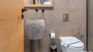 Ein modernes Badezimmer mit einem Steintonne, einer Toilette, einem Spiegel und einer Dusche.