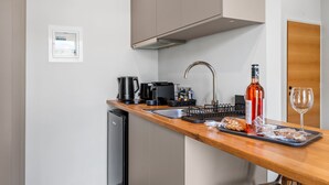 Eine kleine Küchenzeile mit Spüle, Kaffeemaschine und einer Weinflasche auf der Arbeitsfläche.
