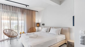 A modern hotel room with a large bed, a chair, a bedside table, and a lamp. - Sea View Suite  First Floor (Nikiana)