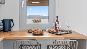 Una encimera de cocina con una cafetera, pasteles, una botella de vino y vasos.