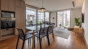 Une cuisine moderne avec un coin repas, de grandes fenêtres et une vue sur les immeubles de grande hauteur.