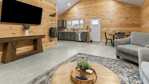 A cozy cabin interior with a living room, kitchen, and dining area, featuring wooden walls and a sloped ceiling. - Acadia Timber Cottages #58 - Minutes to Acadia National Park! (Trenton)