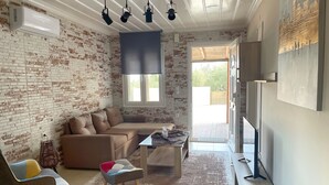 Un salon avec un mur en briques, un canapé, une table basse, un téléviseur et une fenêtre.