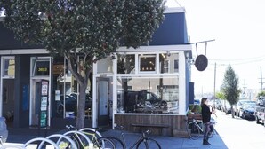 A storefront with a bike parking area, a tree, and parked bicycles. - The Ocean's Edge Studio (SF)