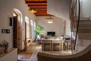 Ein geräumiges Wohnzimmer mit Holzboden, einem großen Fernseher und einer Treppe, die zu einer oberen Etage führt.