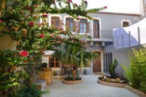 A courtyard with a palm tree, potted plants, and a stone bench. - Triada  Manor  House (Heraklion)