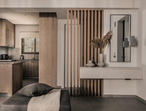 Ein modernes Interieur mit einer Holzwand, einem minimalistischen Sofa, einem weißen Konsolentisch mit Vasen und einem großen Spiegel.