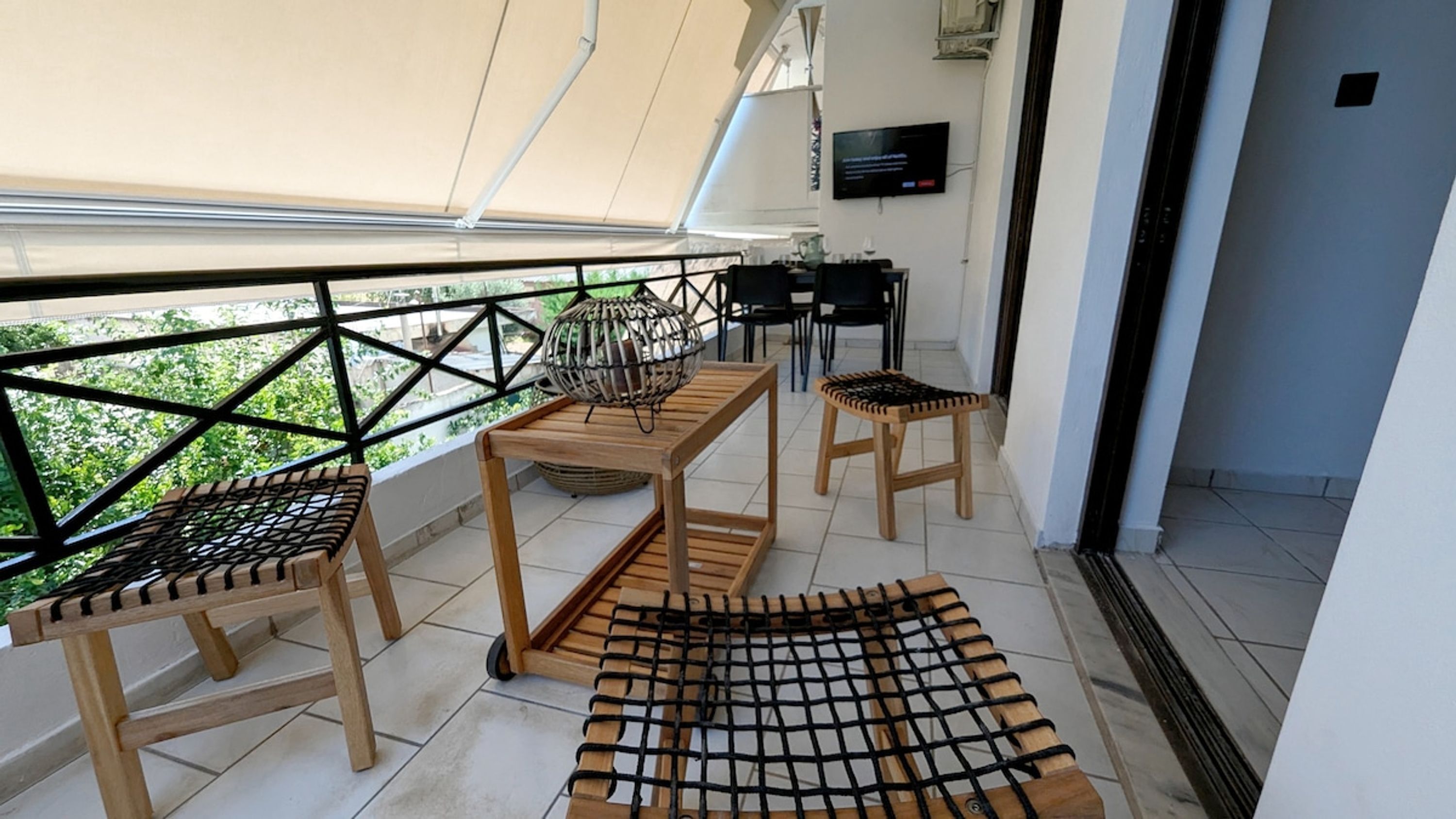 Un balcon agrémenté de meubles en bois, notamment deux chaises et une table, ainsi qu’un panier décoratif en osier tressé.